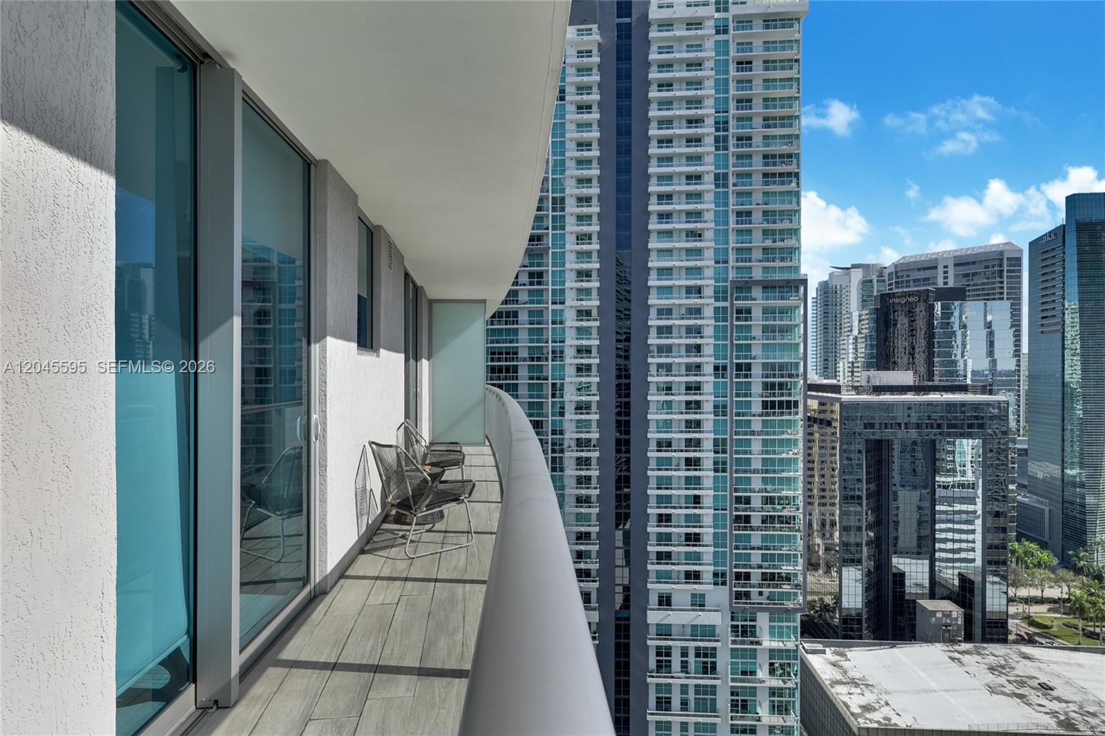 A high-rise balcony with gray wood-look tile flooring overlooks a dense urban skyline — 1100 S Miami Ave # 2504, Miami FL 33130, MIAMI, FL
