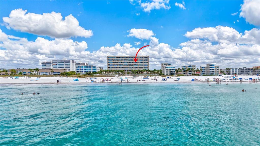 An aerial view of a multi-story beachfront condominium building with a red arrow pointing down — 6140 MIDNIGHT PASS ROAD UNIT 603, SARASOTA, FL
