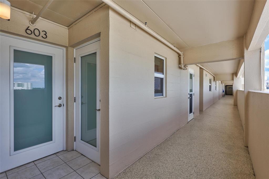 An outdoor apartment corridor features a unit entrance labeled 603 with a frosted glass door — 6140 MIDNIGHT PASS ROAD UNIT 603, SARASOTA, FL