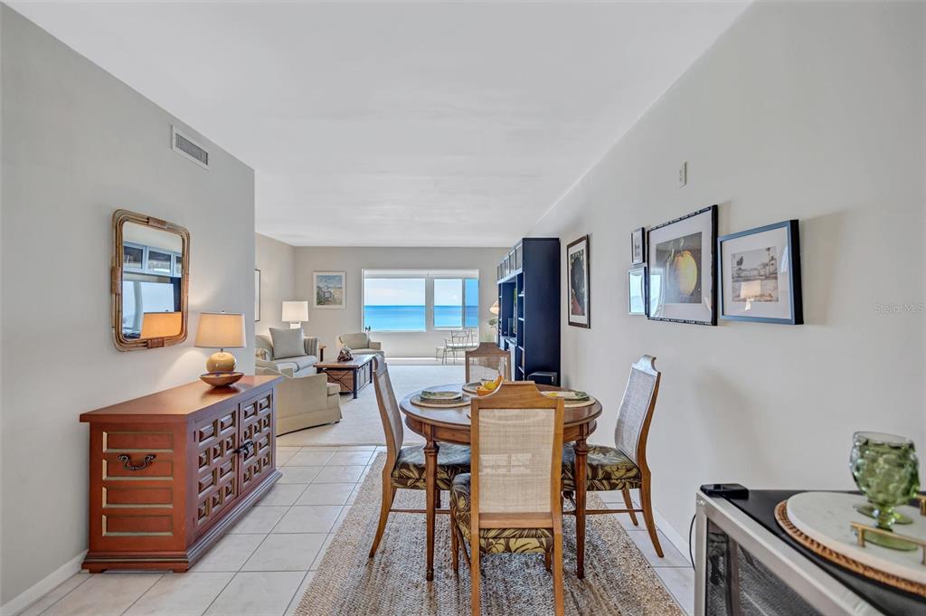 A dining area and living room with tile floors overlook the ocean through a window — 6140 MIDNIGHT PASS ROAD UNIT 603, SARASOTA, FL