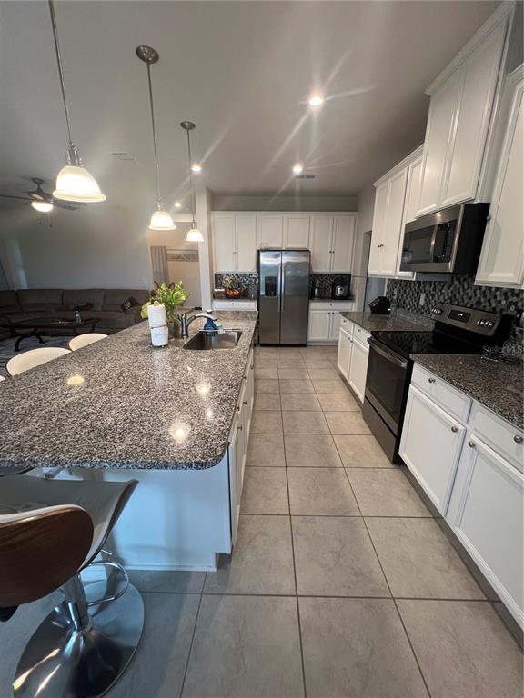 A kitchen features white cabinets, granite countertops, a large island, and stainless steel appliances — 2937 SLOUGH CREEK DRIVE, KISSIMMEE, FL