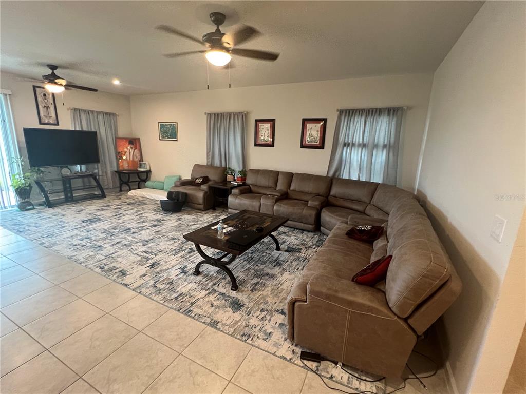 A living room features a large sectional sofa, a coffee table, and a patterned area rug — 2937 SLOUGH CREEK DRIVE, KISSIMMEE, FL