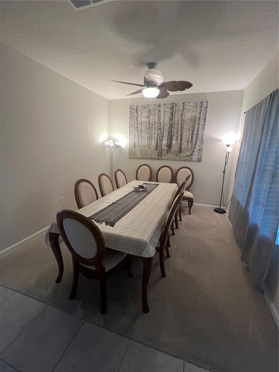 A dining room features a long table with eight chairs, a ceiling fan, and wall art — 2937 SLOUGH CREEK DRIVE, KISSIMMEE, FL