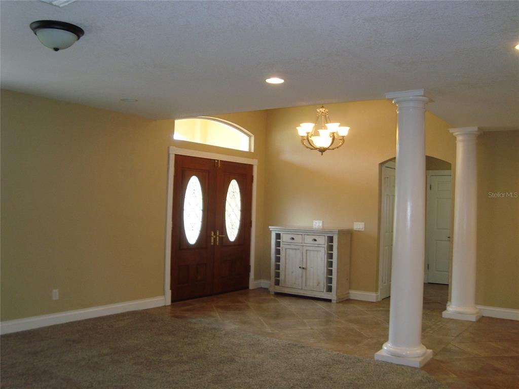 An entryway features a double wood door, tile flooring, carpeted area, and two white columns — 601 PALM AVENUE, BELLEAIR, FL