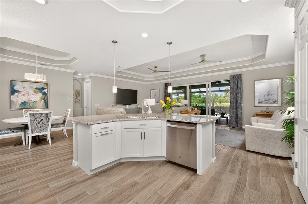A kitchen island with a stainless steel dishwasher faces a dining area and living room — 25180 LONGMEADOW DRIVE, PUNTA GORDA, FL