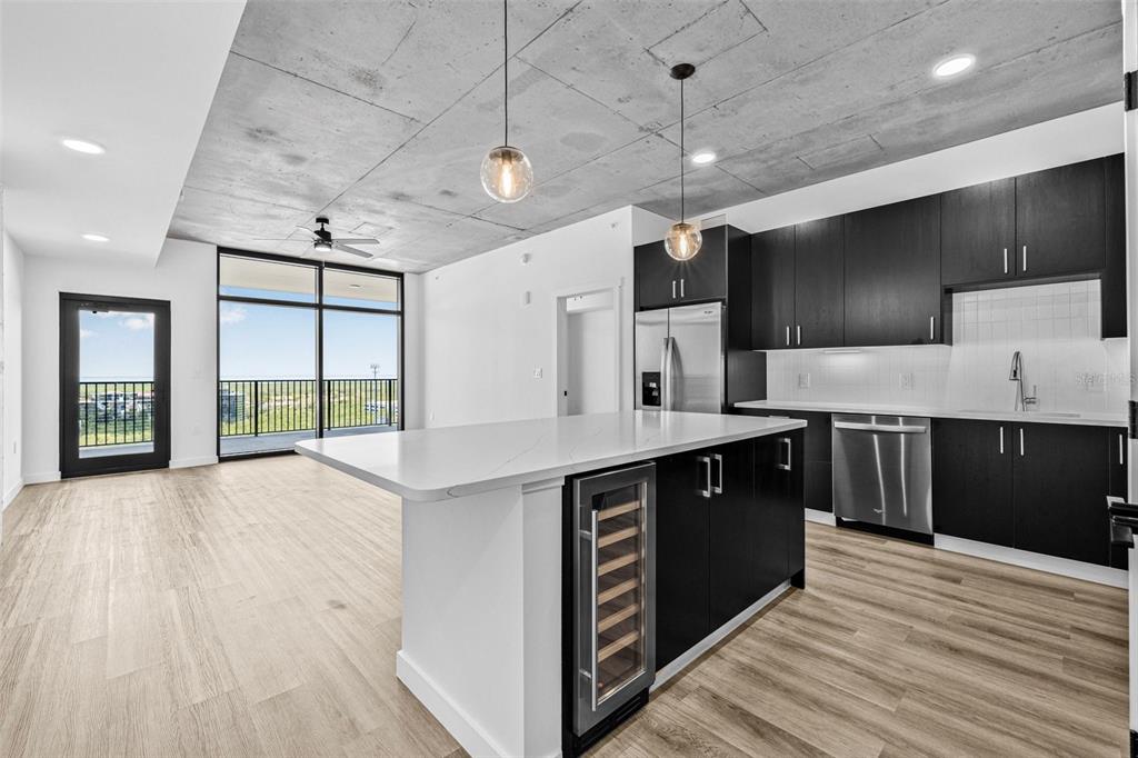 A modern kitchen features dark cabinetry, a white island with a wine cooler, and concrete ceilings — 221 MAIN STREET N UNIT B2-1010, ST PETERSBURG, FL