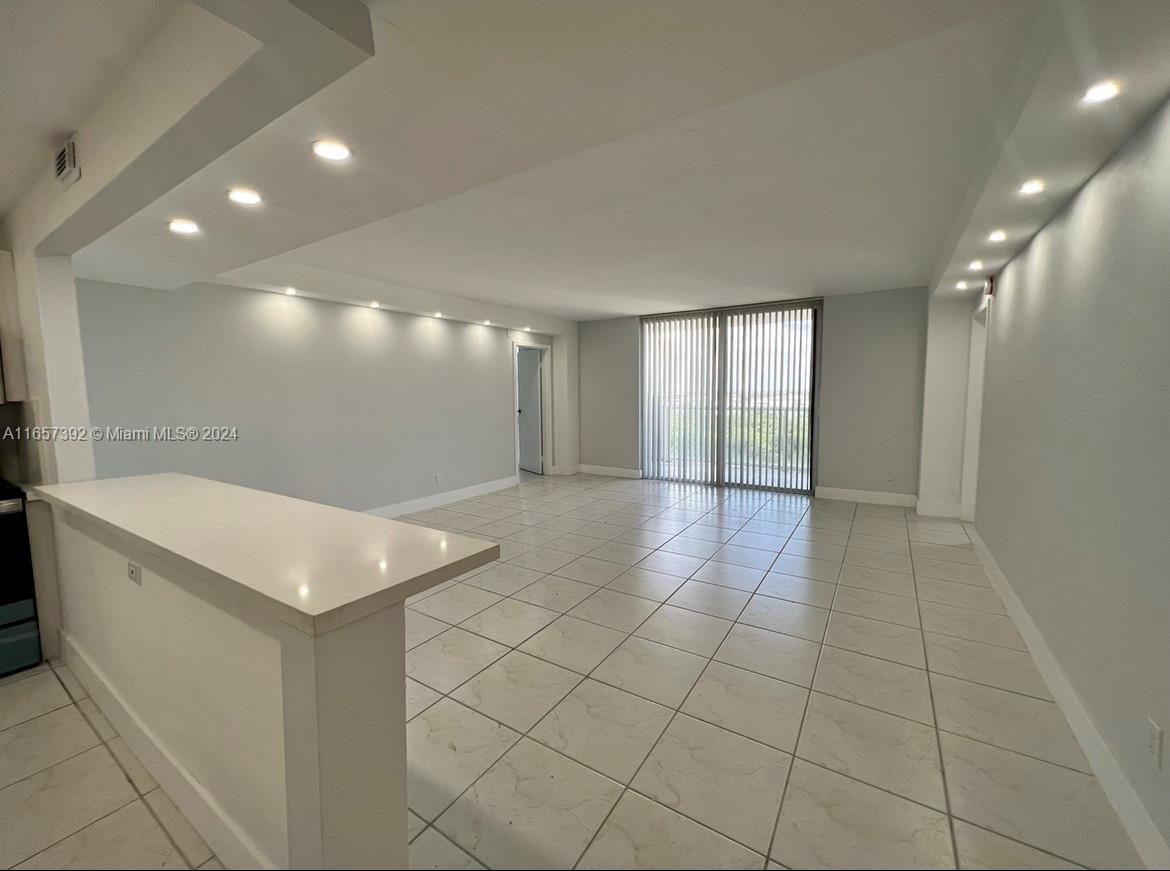 An open-concept living and dining area features white tile flooring and recessed ceiling lighting — 13499 Biscayne Blvd # 1405, North Miami FL 33181, NORTH MIAMI, FL