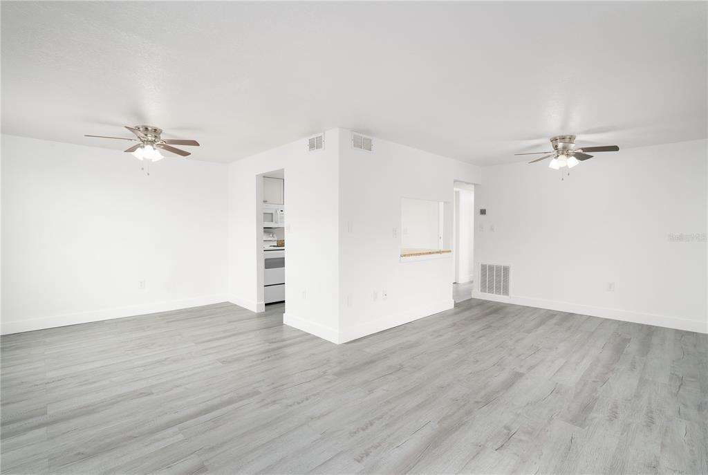 An empty room with white walls, gray wood-look flooring, and two ceiling fans — 22291 WESTCHESTER BOULEVARD UNIT 206, PORT CHARLOTTE, FL