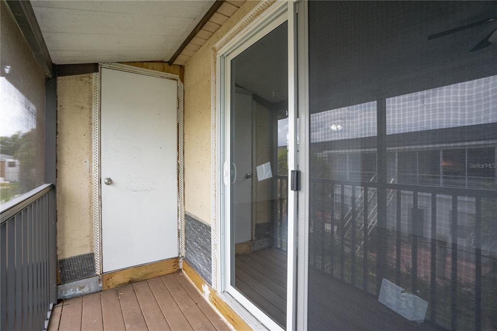 A balcony features a white door, a sliding glass door, and unfinished wall surfaces — 22291 WESTCHESTER BOULEVARD UNIT 206, PORT CHARLOTTE, FL
