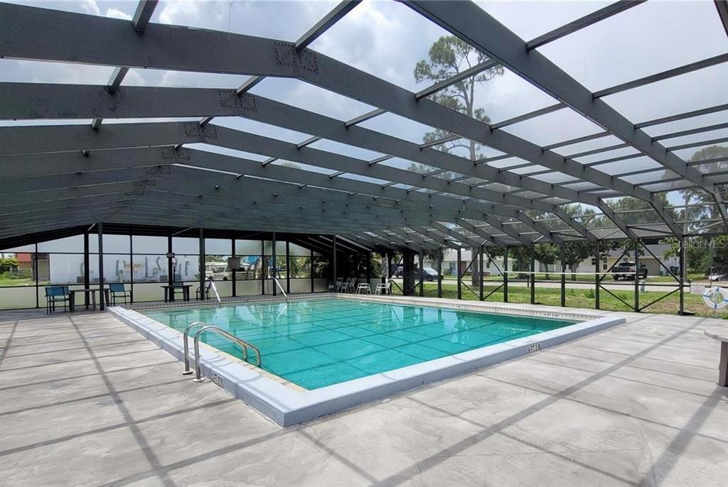 A rectangular swimming pool is enclosed by a large screened-in metal frame structure — 22291 WESTCHESTER BOULEVARD UNIT 206, PORT CHARLOTTE, FL