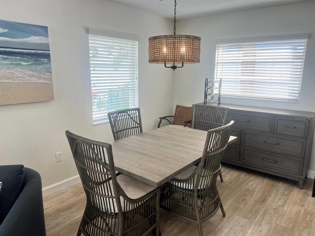A dining room features a wooden table, four rattan chairs, and a woven pendant light — 6020 MIDNIGHT PASS ROAD UNIT 36, SARASOTA, FL