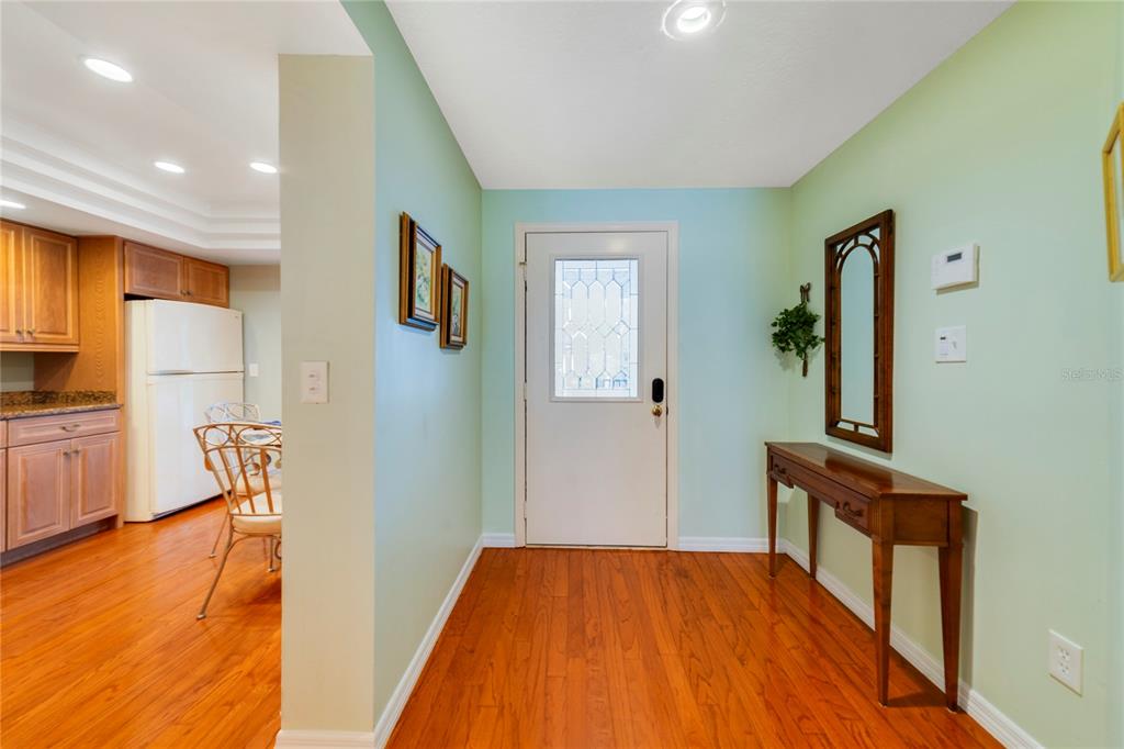 An entryway with light green walls, wood flooring, a console table, and a white door — 1055 KENSINGTON PARK DRIVE UNIT 812, ALTAMONTE SPRINGS, FL
