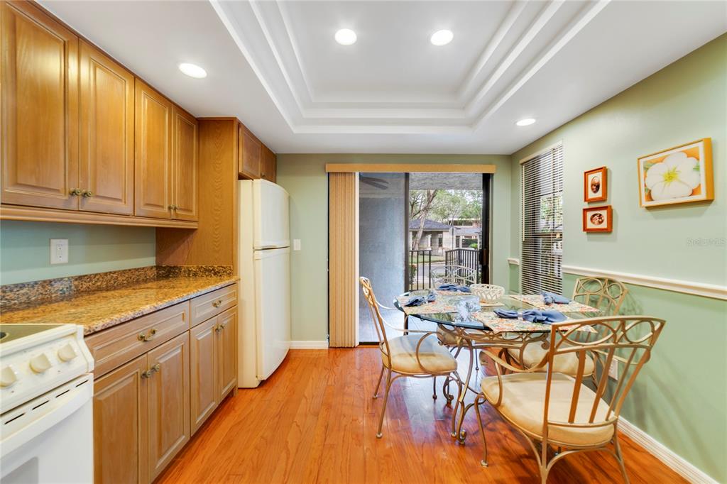 A kitchen with wood cabinets, granite countertops, and a dining area with a sliding door — 1055 KENSINGTON PARK DRIVE UNIT 812, ALTAMONTE SPRINGS, FL