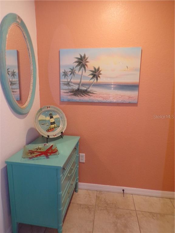 A teal dresser sits against a peach wall beneath a beach-themed painting and mirror — 1462 RIO DE JANEIRO AVENUE UNIT B103, PUNTA GORDA, FL
