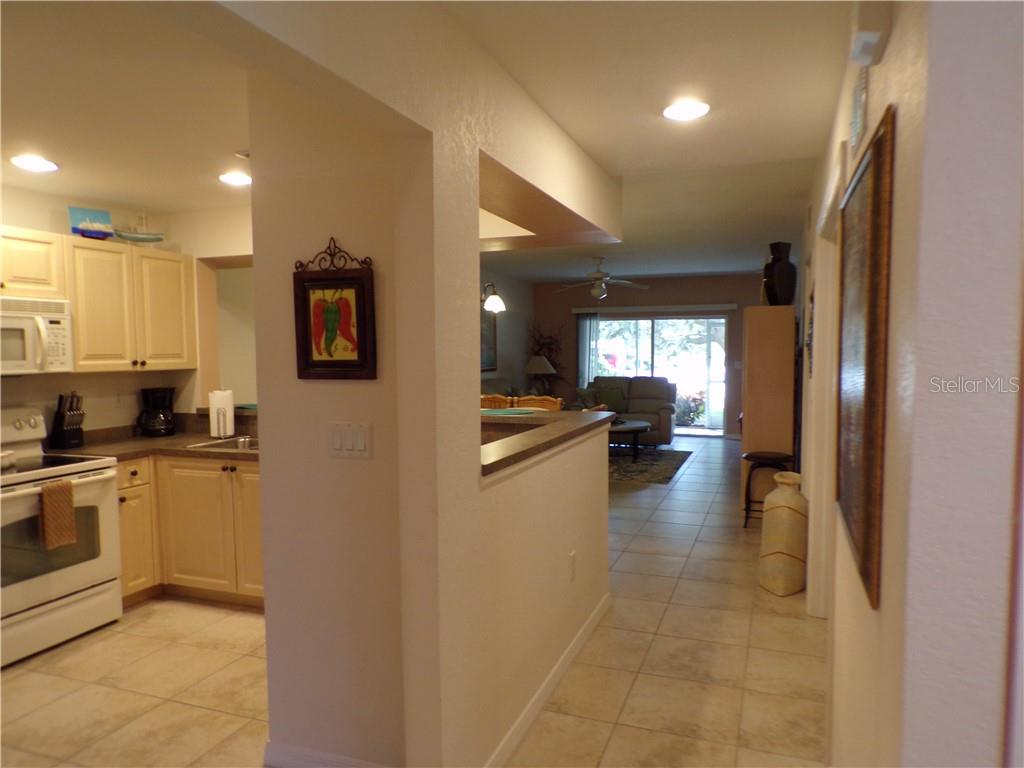 A kitchen with light cabinets and tile floors opens into a living area with sliding doors — 1462 RIO DE JANEIRO AVENUE UNIT B103, PUNTA GORDA, FL