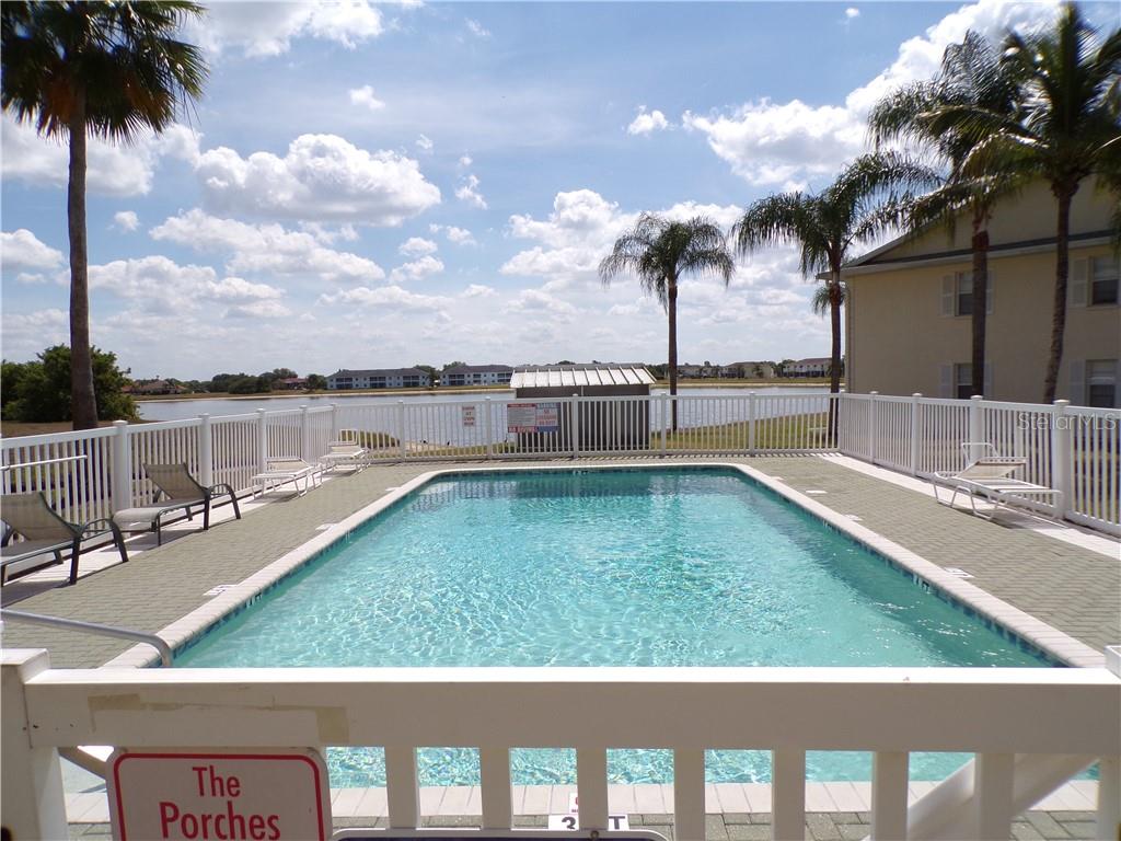 A rectangular swimming pool is surrounded by a white fence, lounge chairs, and palm trees — 1462 RIO DE JANEIRO AVENUE UNIT B103, PUNTA GORDA, FL