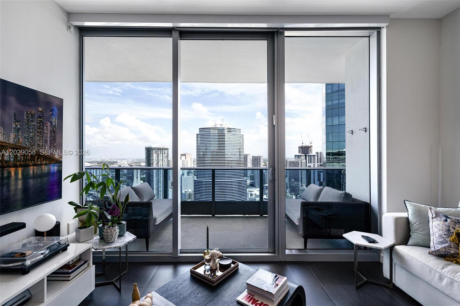 A living room features floor-to-ceiling sliding glass doors opening onto a balcony with city views — 200 Biscayne Boulevard Way # 4812, Miami FL 33131, MIAMI, FL