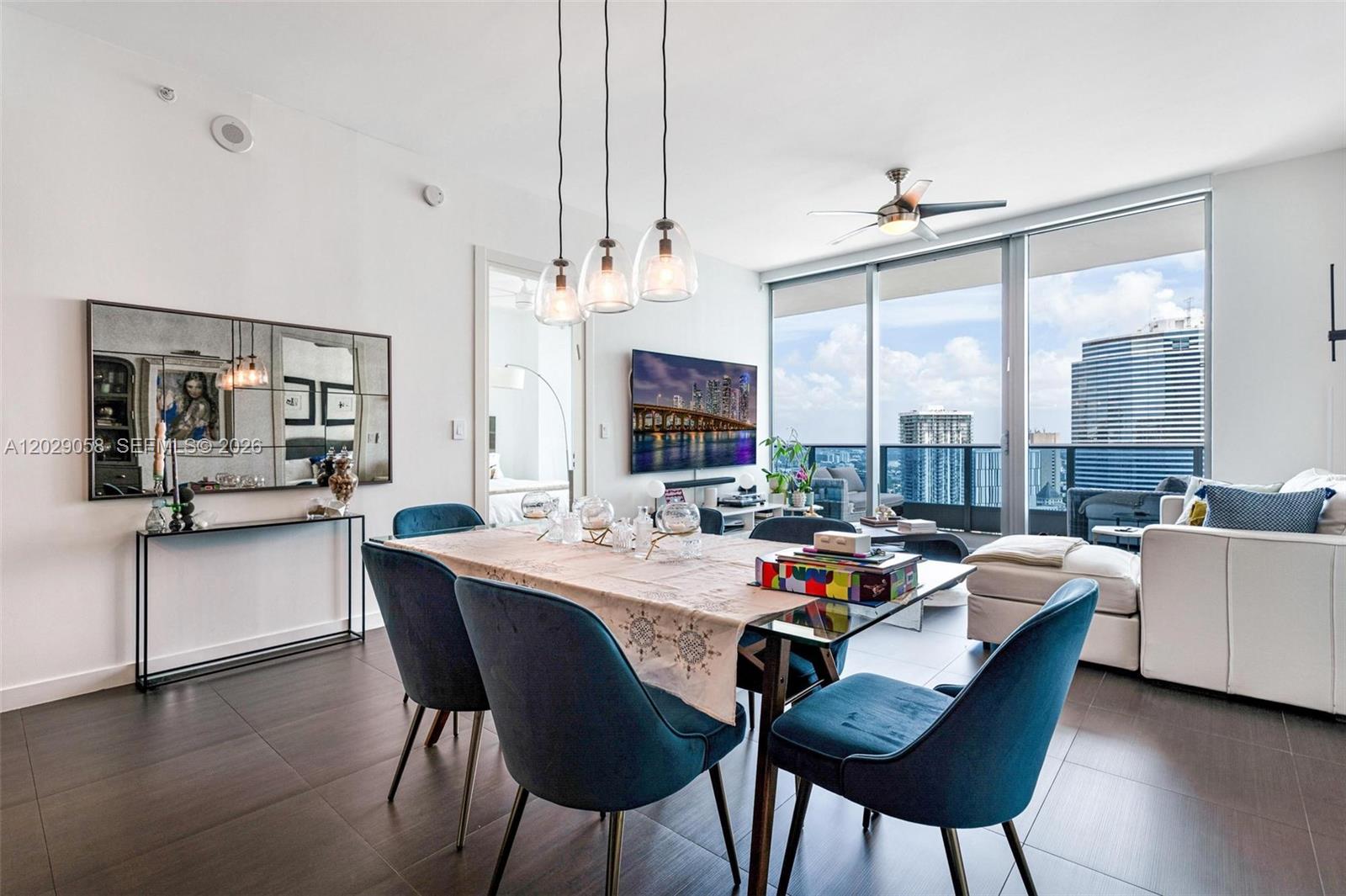 A dining area with blue chairs and a glass table sits before a living room — 200 Biscayne Boulevard Way # 4812, Miami FL 33131, MIAMI, FL