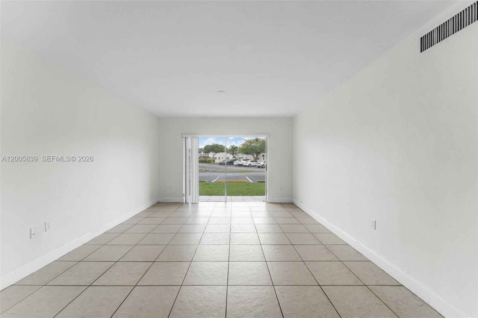 An empty room features white walls, light-colored tile flooring, and a sliding glass door — 7560 SW 82nd St # G112, Miami FL 33143, MIAMI, FL