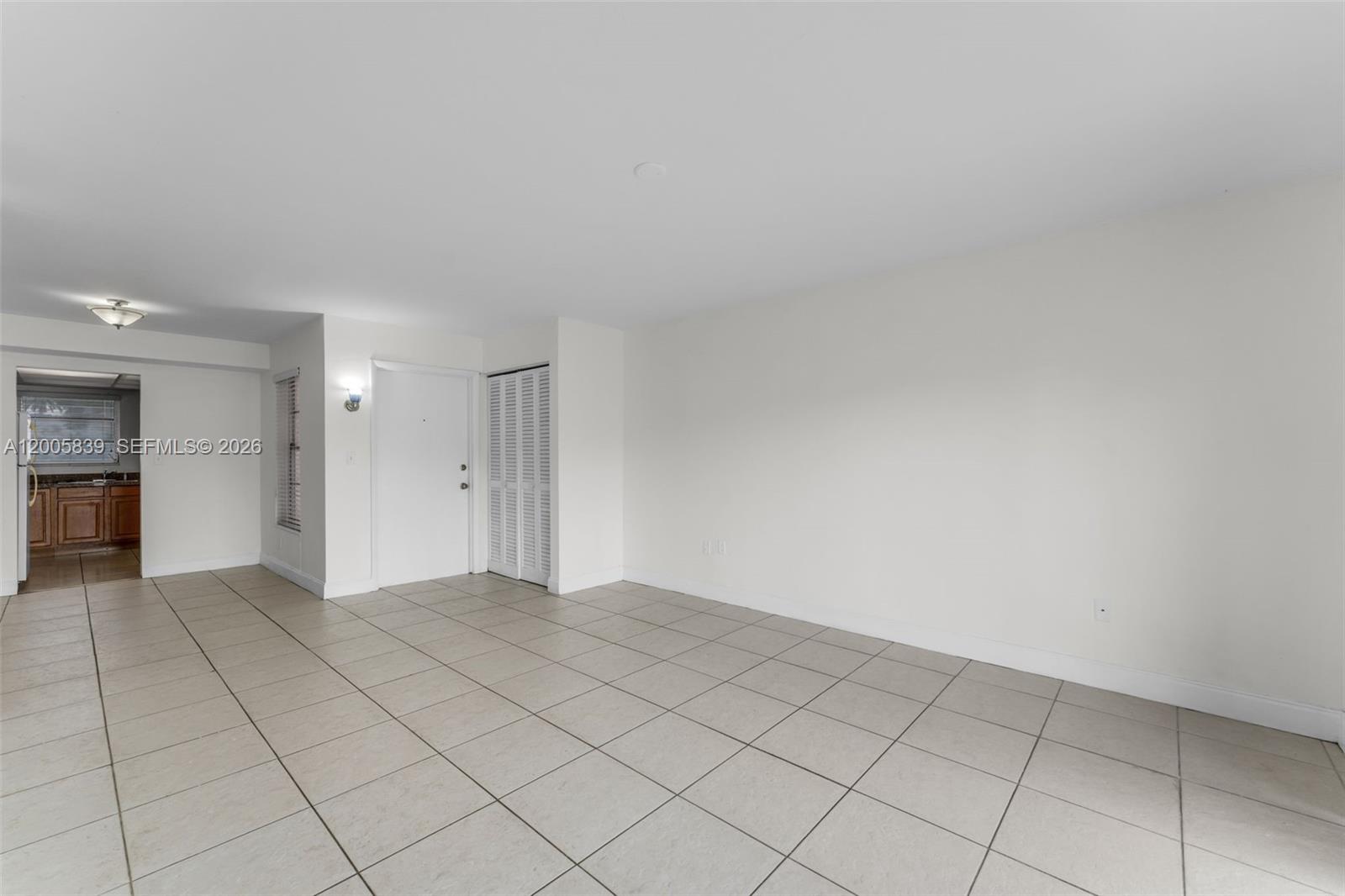 A bright, empty room features light-colored tile flooring, white walls, and a white entry door — 7560 SW 82nd St # G112, Miami FL 33143, MIAMI, FL