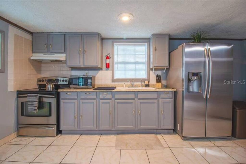 A kitchen with gray cabinets, stainless steel appliances, and light-colored tile flooring — 1731 GRAYSON DRIVE, ORLANDO, FL