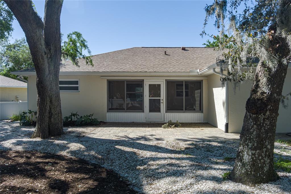 The exterior of a house features a paved patio, a screened-in porch, and large trees — 9206 31ST STREET COURT E, PARRISH, FL
