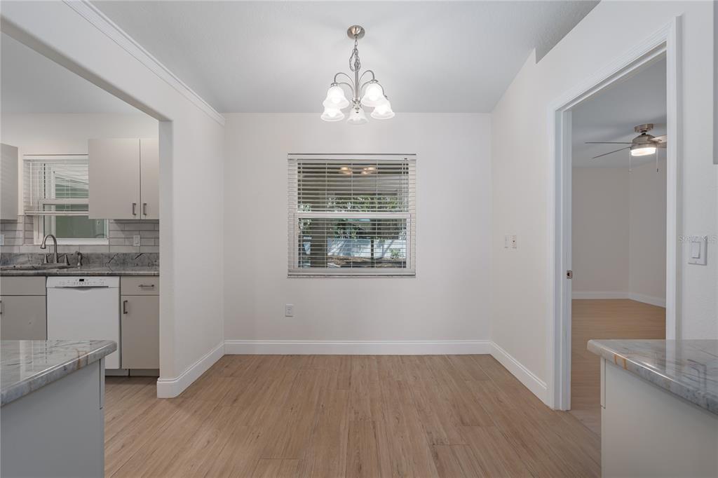 A dining area with light wood flooring, a central chandelier, and a window with blinds — 9206 31ST STREET COURT E, PARRISH, FL