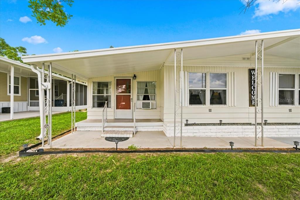 The exterior of a mobile home features a concrete porch, metal supports, and a welcome sign — 7505 FAIRLANE AVENUE, BROOKSVILLE, FL