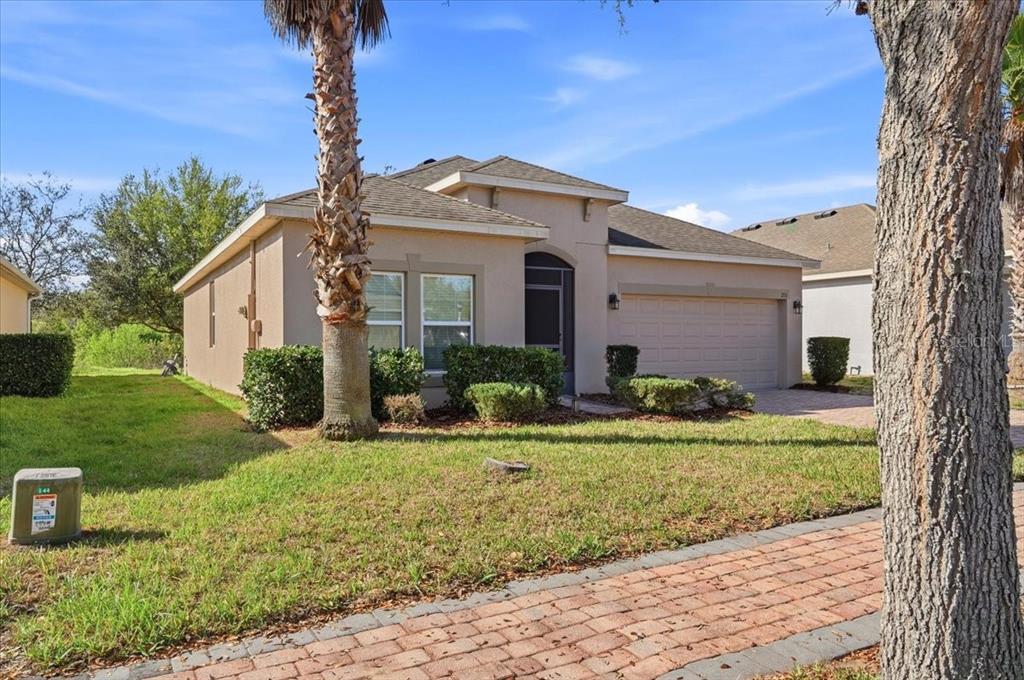 A single-story beige house with a two-car garage and a palm tree in the yard — 215 LAKESHORE DRIVE, DAVENPORT, FL