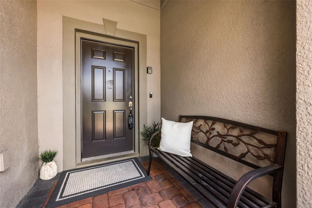 A front entryway features a dark brown door, a metal bench, and a paved floor — 215 LAKESHORE DRIVE, DAVENPORT, FL