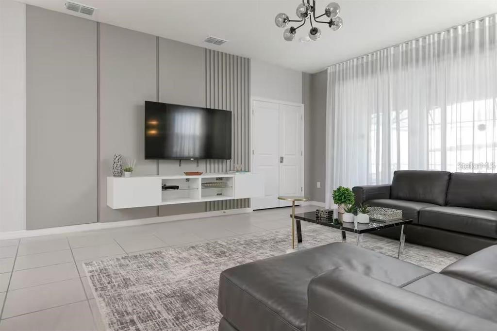 A modern living room features a wall-mounted television, a floating console, and gray leather furniture — 1671 KONA LANE, DAVENPORT, FL