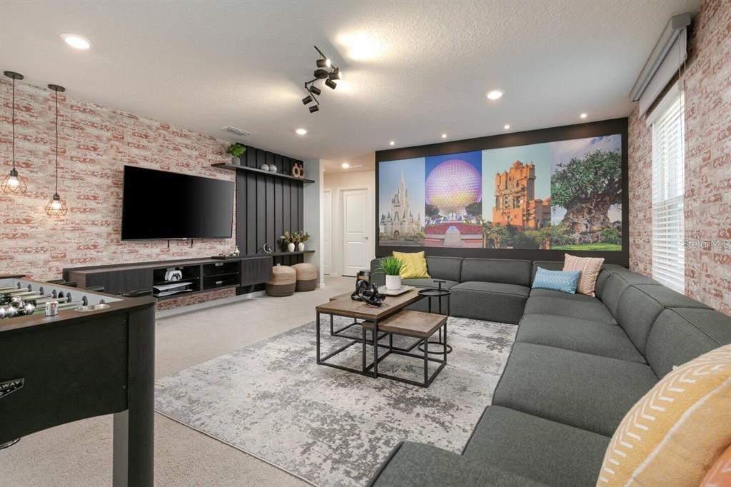 A living room features a large sectional sofa, a wall mural of Disney landmarks, and brick-patterned wallpaper — 1671 KONA LANE, DAVENPORT, FL