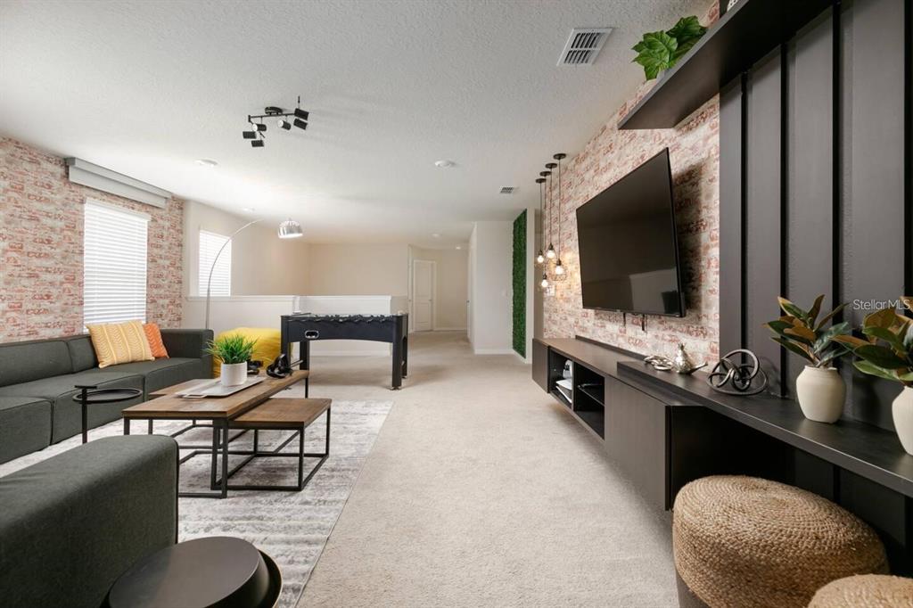 A living room features a brick accent wall, a large television, and a foosball table — 1671 KONA LANE, DAVENPORT, FL