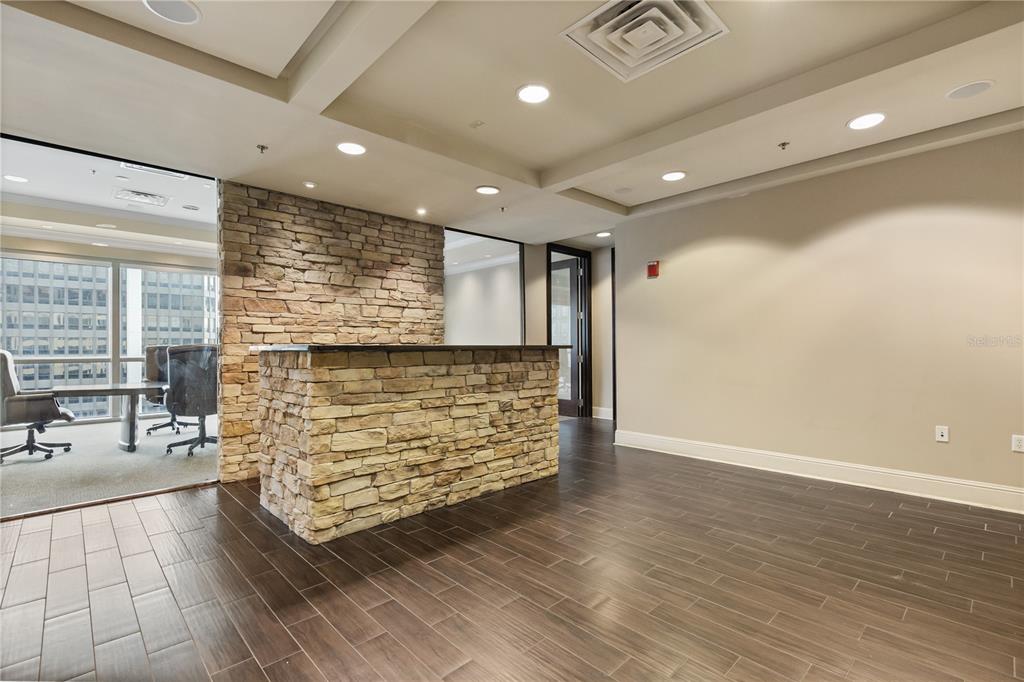 A stone-clad reception desk sits in an office space with wood-look tile flooring — 189 S ORANGE AVENUE UNIT 1430,1450,1470, ORLANDO, FL