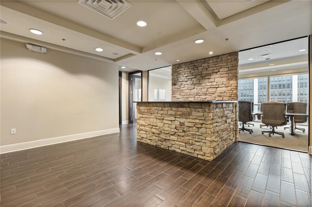 A modern office space features a stone-faced reception desk, dark wood flooring, and recessed lighting — 189 S ORANGE AVENUE UNIT 1430,1450,1470, ORLANDO, FL