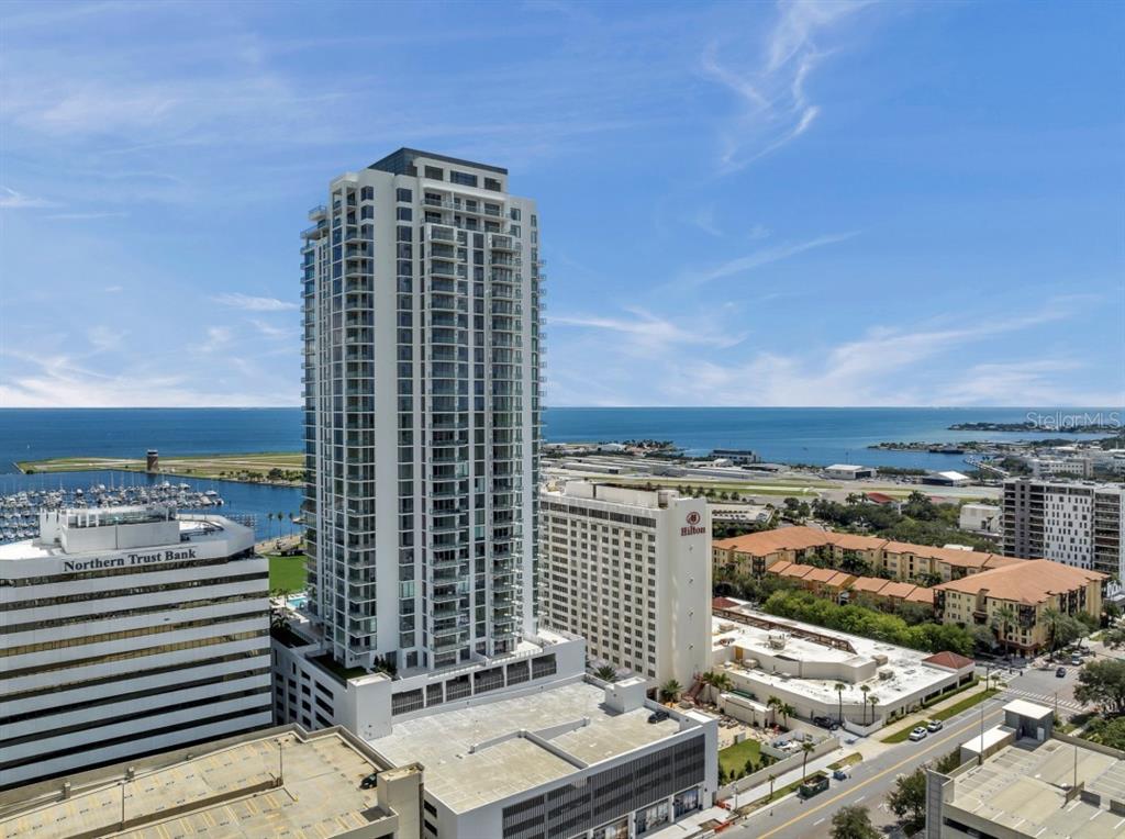 An aerial view shows a tall residential skyscraper next to a Hilton hotel and bay — 301 1ST STREET S UNIT 1704, ST PETERSBURG, FL