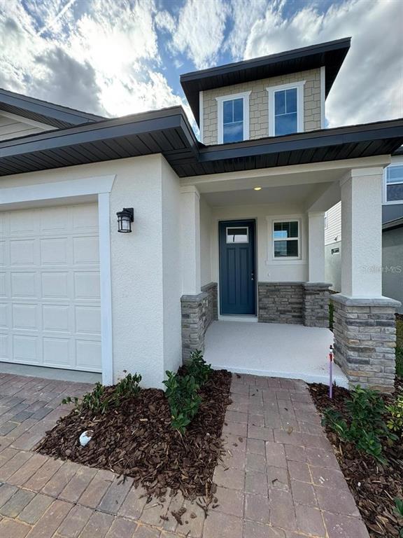 The exterior of a modern house features a blue front door, stone accents, and a driveway — 2297 TREASURE HILL STREET, MINNEOLA, FL