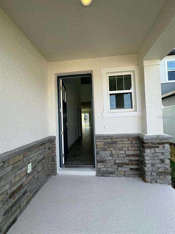 A covered porch features stone veneer siding, a single front door, and a window — 2297 TREASURE HILL STREET, MINNEOLA, FL