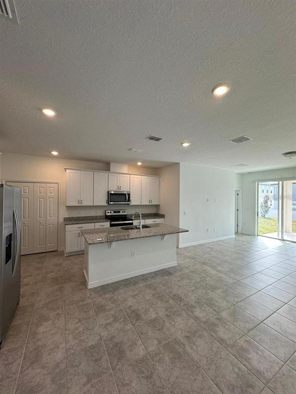 A kitchen with white cabinets, granite countertops, an island, and tile flooring — 2297 TREASURE HILL STREET, MINNEOLA, FL