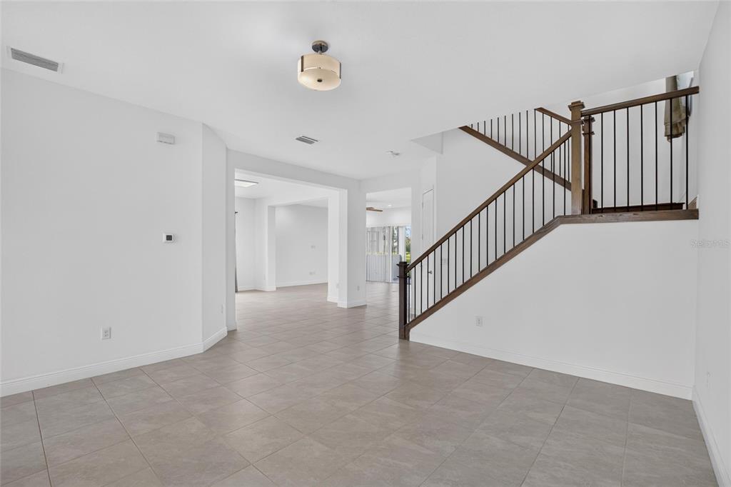 An interior view shows a tiled foyer with a staircase featuring dark wood railings — 31142 LINDENTREE DRIVE, WESLEY CHAPEL, FL