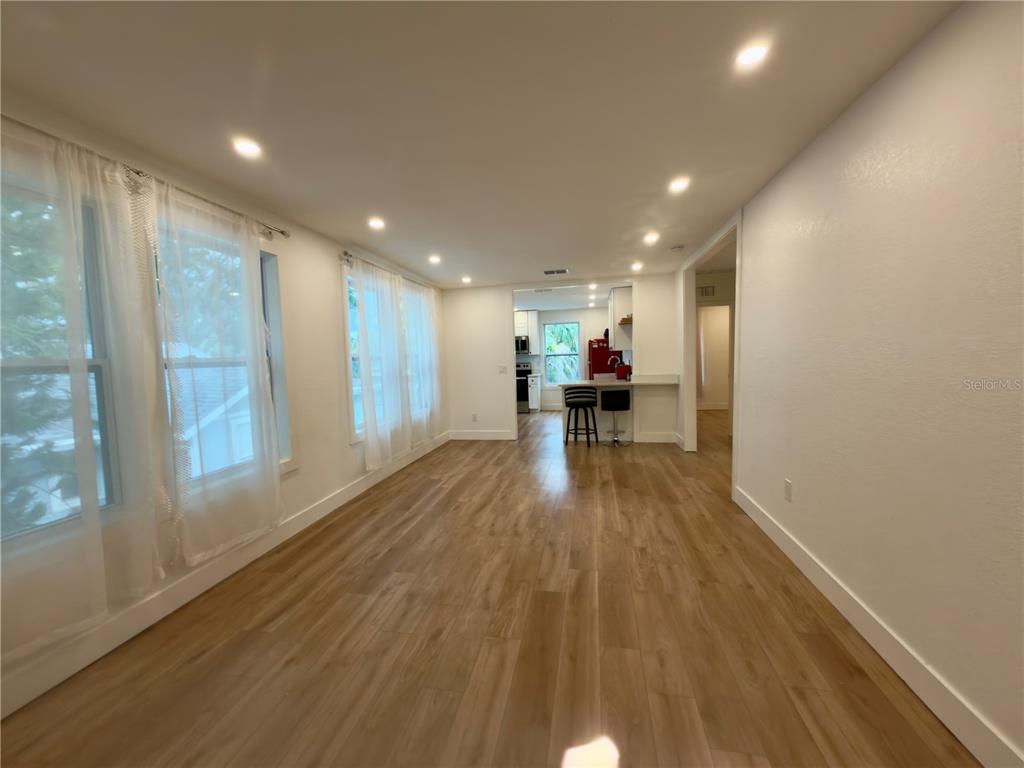 A bright living room features light wood floors, a beige sofa, and an open kitchen — 2238 QUINCY STREET S, ST PETERSBURG, FL