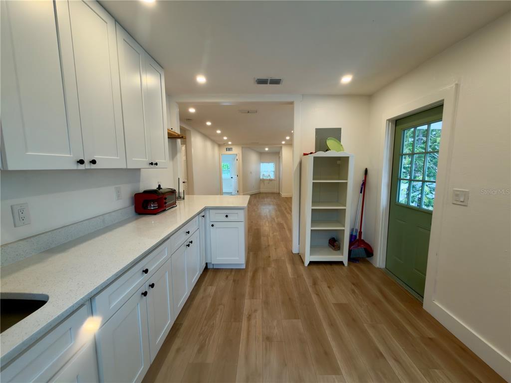 A bright living area with light wood-look flooring leads to an open kitchen with bar seating — 2238 QUINCY STREET S, ST PETERSBURG, FL