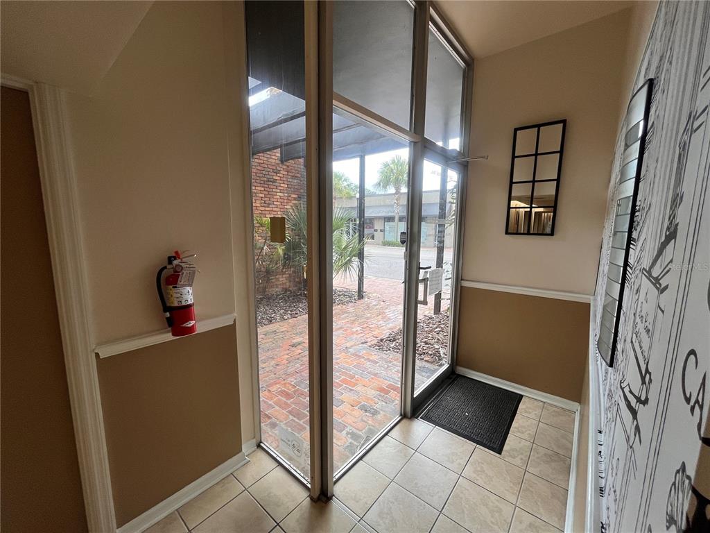 An interior entryway features tiled flooring, a fire extinguisher, and a glass door to outside — 141 W CENTRAL AVENUE UNIT 16, WINTER HAVEN, FL