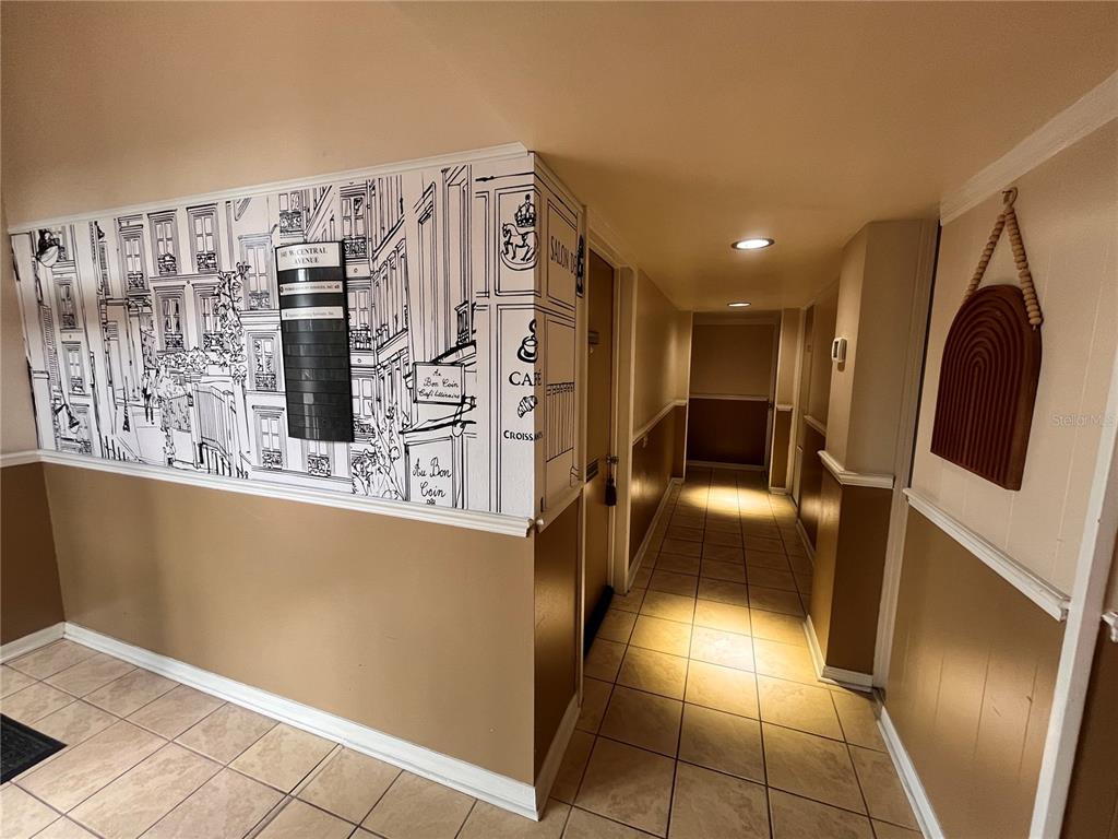 A hallway features tiled floors, tan wainscoting, and a wall mural depicting a Parisian street scene — 141 W CENTRAL AVENUE UNIT 16, WINTER HAVEN, FL