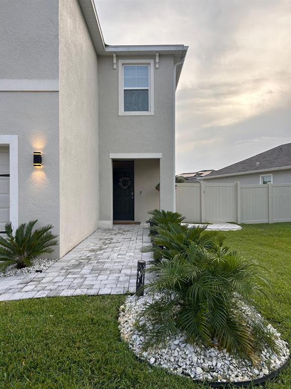 The exterior of a house features a paved walkway, landscaping, and a covered entryway — 32804 BROOKS HAWK LN, WESLEY CHAPEL, FL