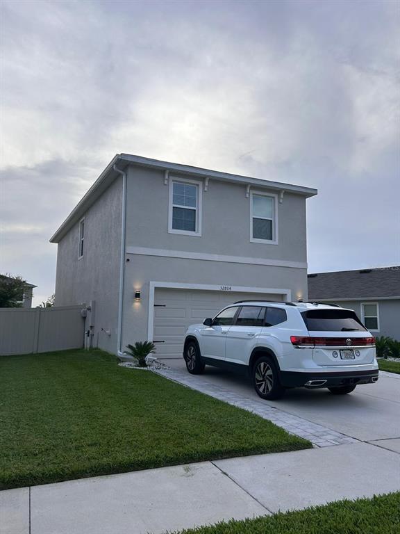 A white SUV is parked in the driveway of a two-story house with light-colored siding — 32804 BROOKS HAWK LN, WESLEY CHAPEL, FL