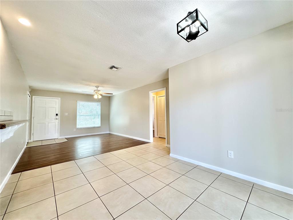 A room features a tiled foreground, wood-look flooring in the background, and a ceiling light — 132 S BULOVA DRIVE, APOPKA, FL