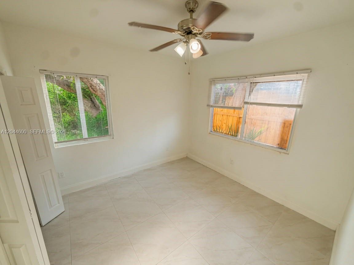An empty bedroom features white walls, tile flooring, a ceiling fan, and two windows — 1154 W 25th St # 0, Riviera Beach FL 33404, RIVIERA BEACH, FL