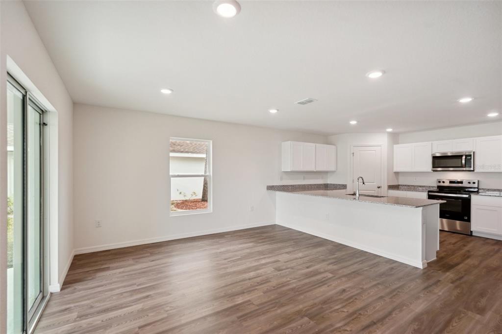 A single-story white house with a two-car garage and a concrete driveway — 14106 EASTERN PHOEBE ROAD, WEEKI WACHEE, FL