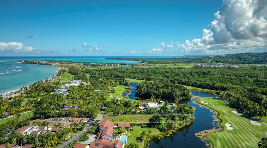 An aerial view shows a coastal golf course with water hazards, lush vegetation, and buildings — 7000 BAHIA BEACH BOULEVARD UNIT 19 Las Estancias, RIO GRANDE, PR